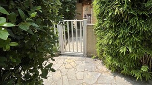 A stone pathway leading to a gated entrance surrounded by dense foliage.