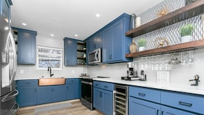 Une cuisine moderne avec des armoires bleues, des appareils en acier inoxydable et un four encastré.