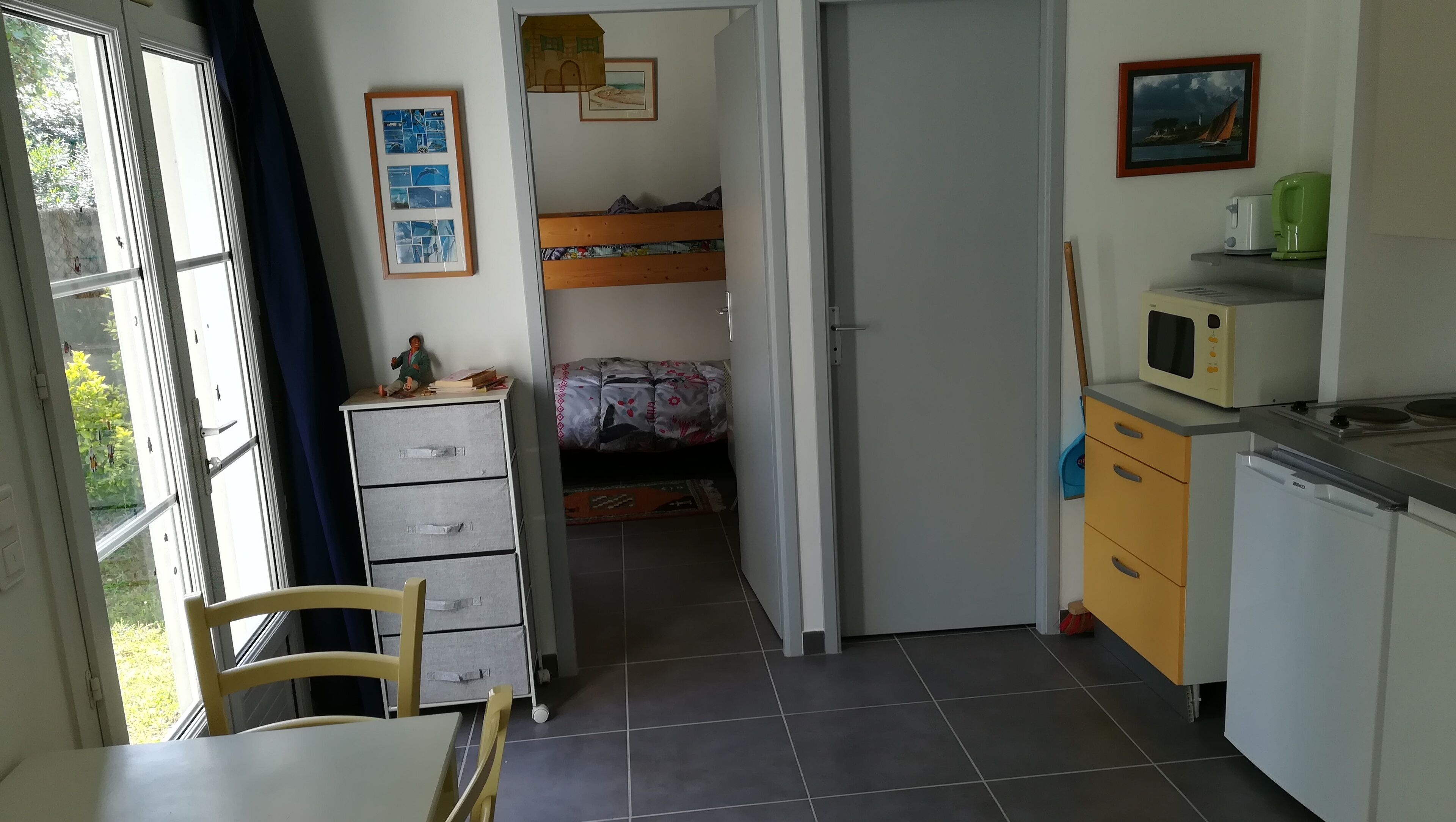 Une petite chambre comprenant un lit, un bureau et une kitchenette.