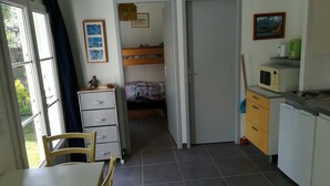 A compact room with a bed, a desk, and a kitchenette.