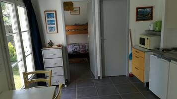 Une petite chambre comprenant un lit, un bureau et une kitchenette.