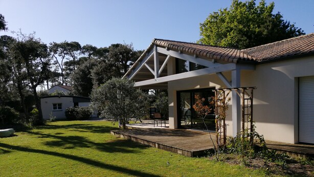 A modern house with a large deck, surrounded by a well-maintained lawn and trees.