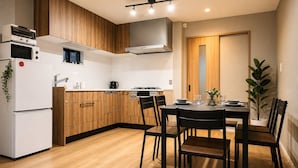 Eine moderne Küche mit Holzausstattung, einem weißen Kühlschrank und einem Essbereich mit Tisch und Stühlen.
