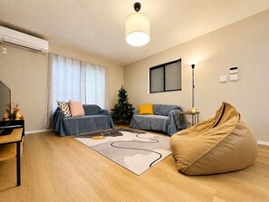 A modern living room with a sofa, a bean bag, a coffee table, and a Christmas tree. - Direct access to Osaka Kansai Airport,5 minutes by train from Nanba (Nishinari-ku, Osaka)