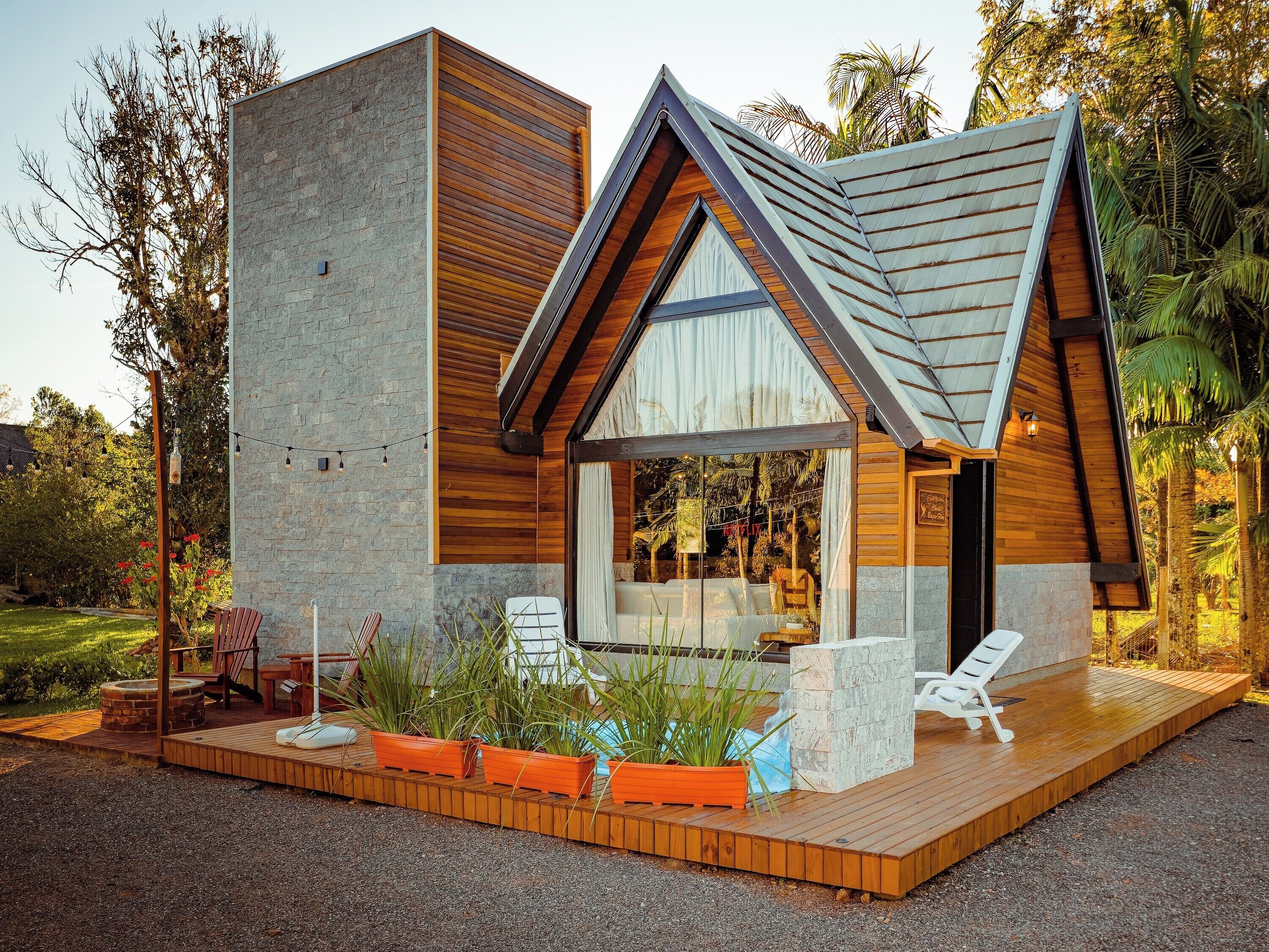 A modern house with a large glass window, wooden deck, and outdoor seating.