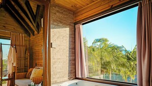 A spa room with a large bathtub, wooden ceiling, and a view of palm trees. - AriMara Chalés & Ecoturismo (Mampituba)