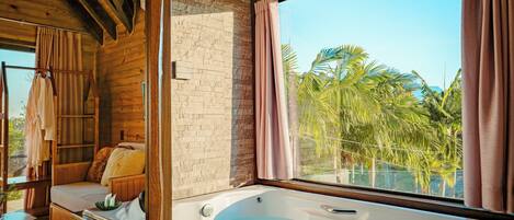 Un cuarto de spa con una bañera grande, techo de madera y vistas a palmeras.