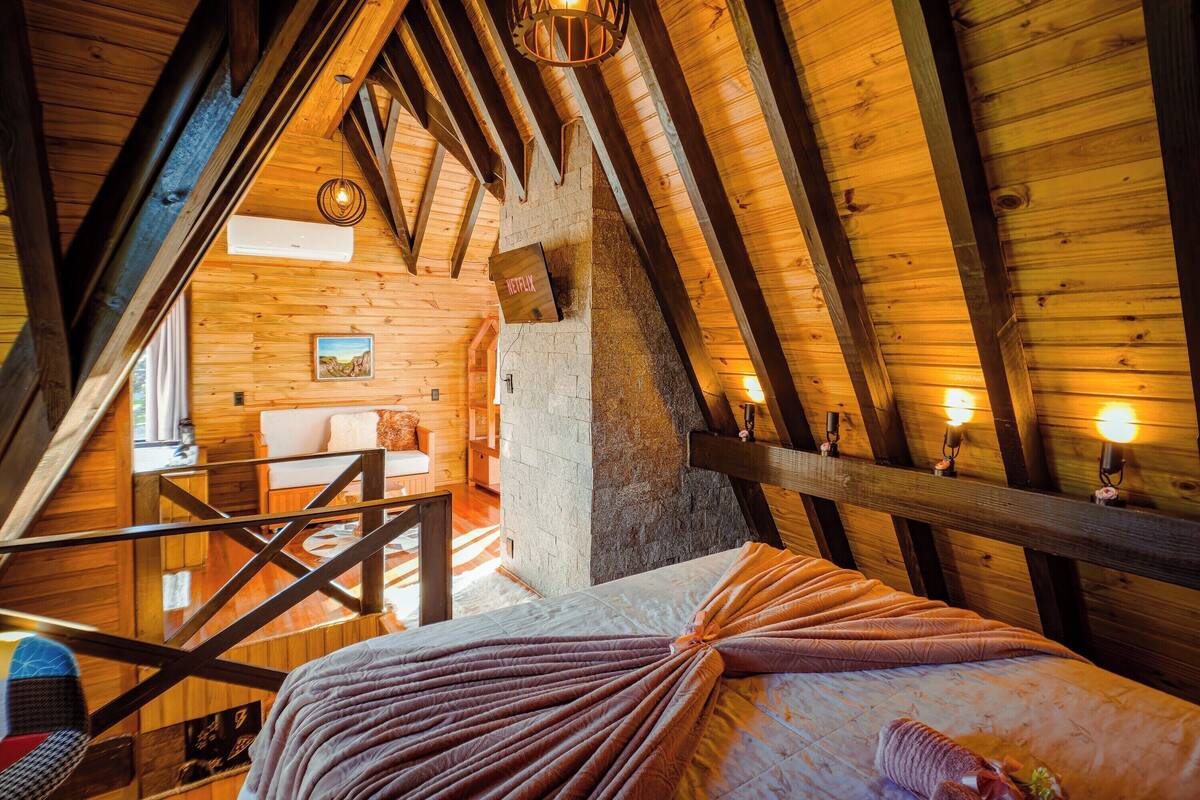Um quarto de sótão aconchegante, com vigas de madeira, uma cama beliche e uma escada.