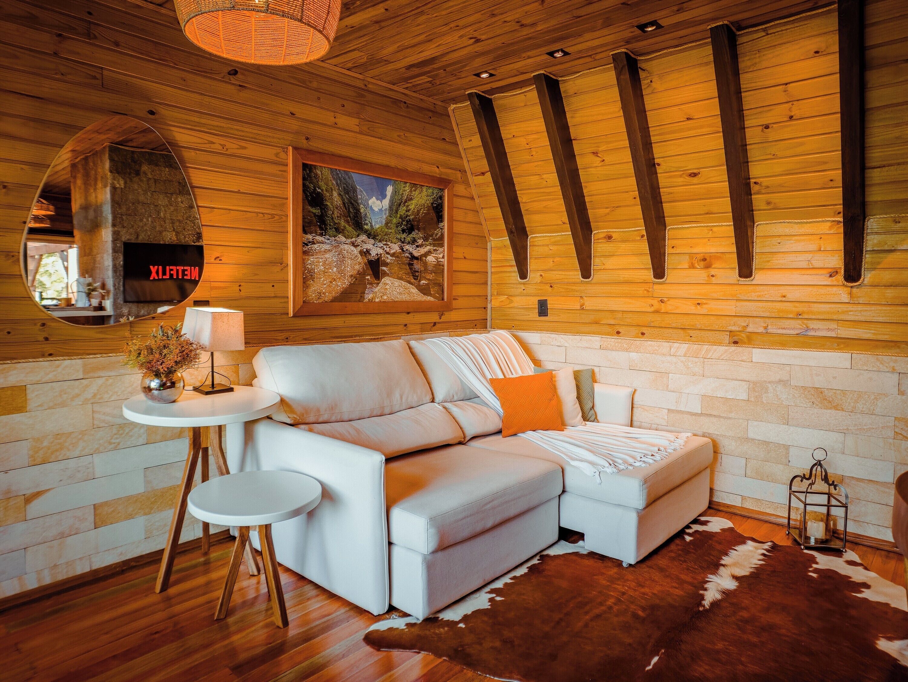 A cozy room with a wooden ceiling, a white sofa, a small round table, and a cowhide rug.