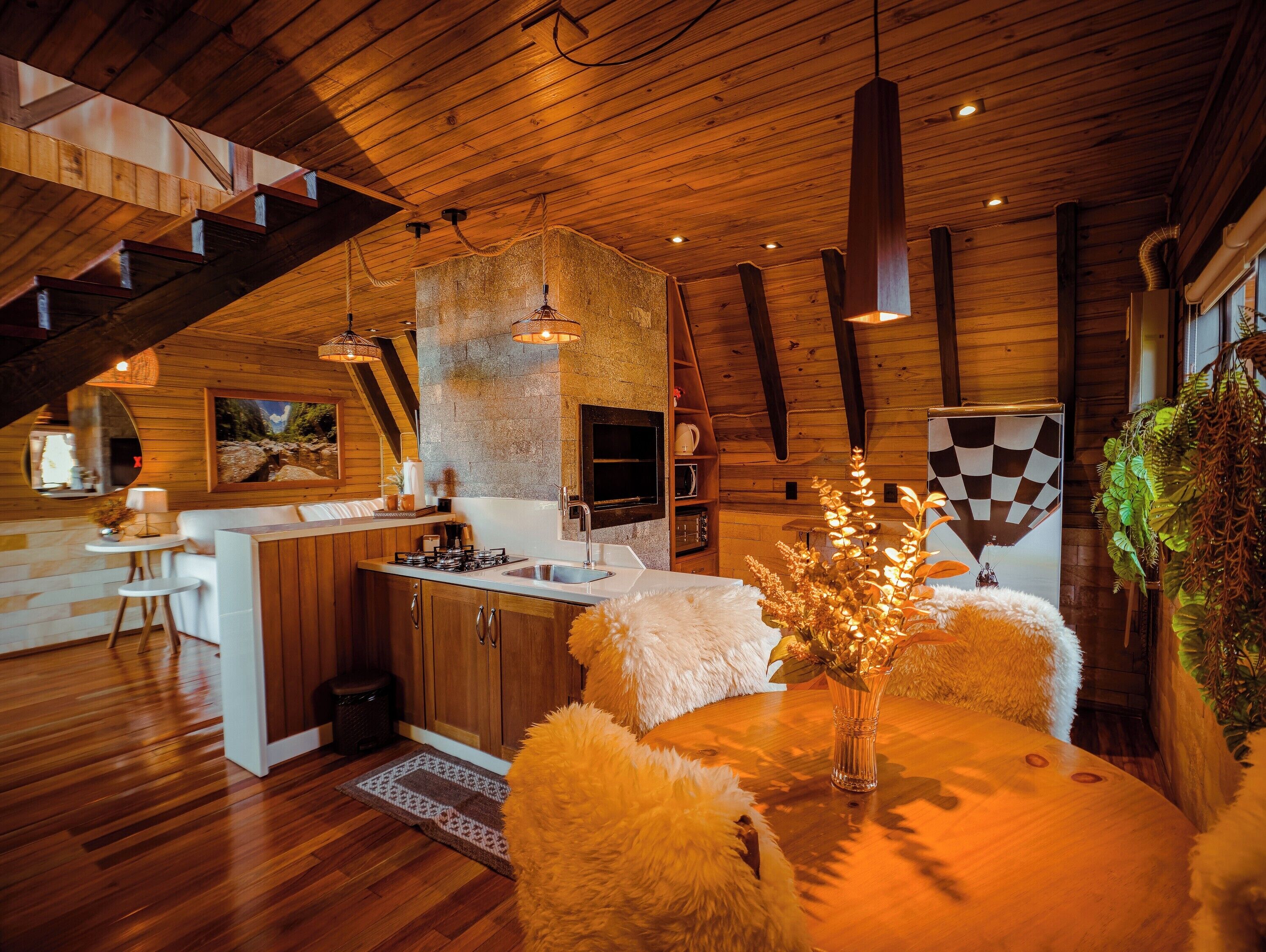 A wooden interior with a kitchen, dining area, and a staircase.