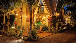 A rustic building with a sloped roof, surrounded by palm trees and a gravel path. - AriMara Chalés & Ecoturismo (Mampituba)