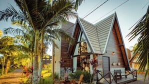 A modern house with a sloped roof, a patio with outdoor furniture, and a well-maintained garden. - AriMara Chalés & Ecoturismo (Mampituba)