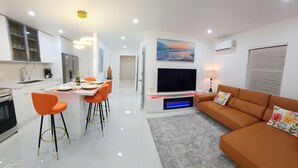 Een moderne woonkamer met een bank, televisie en een eethoek met stoelen en een tafel.