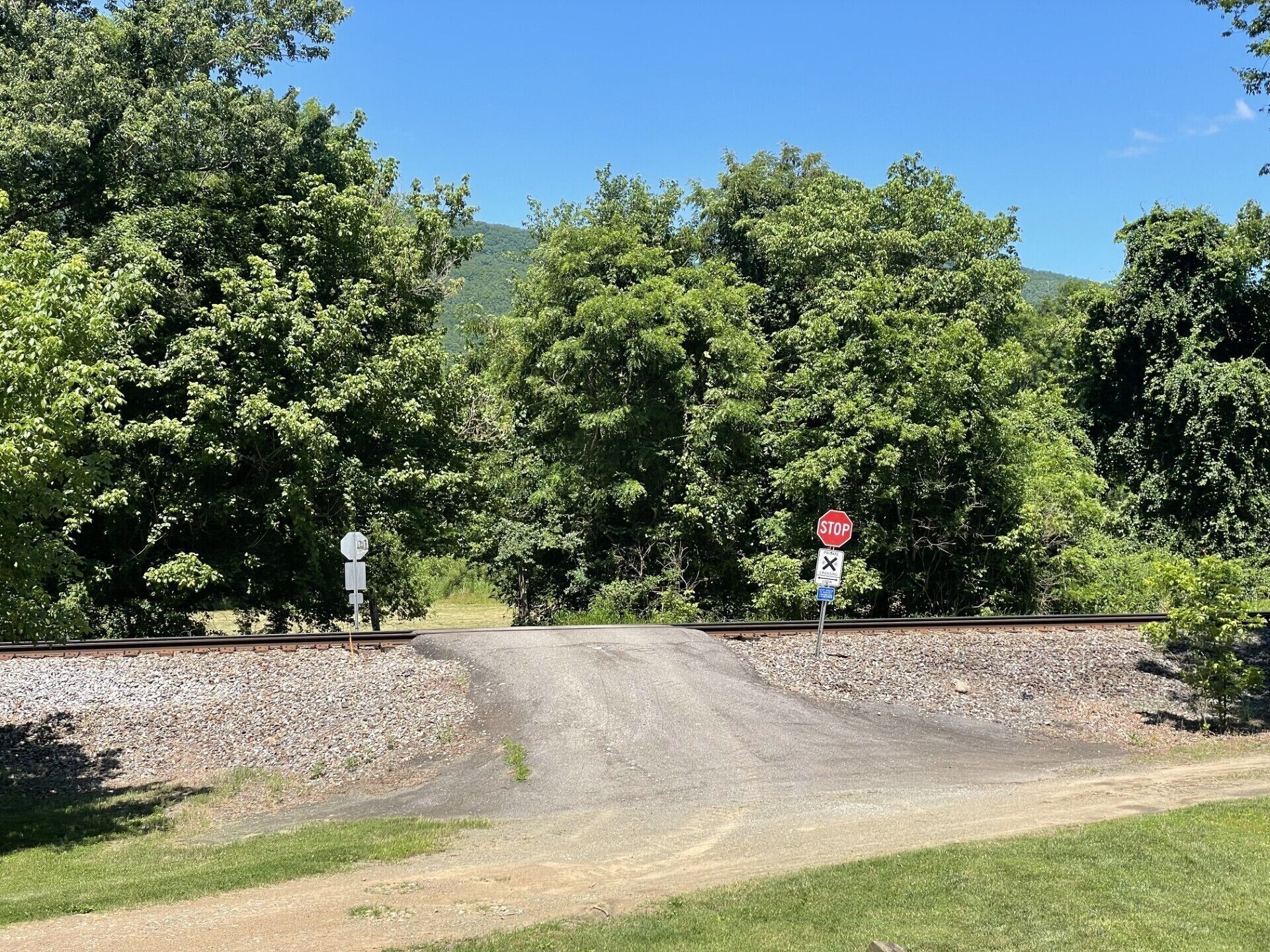 A rural road intersection with a stop sign and a railroad crossing sign.