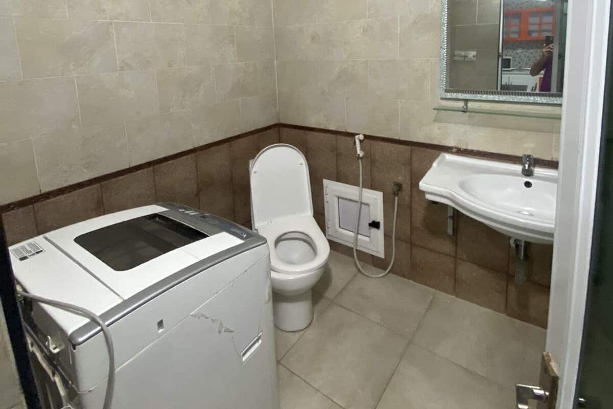 A compact bathroom with a toilet, a sink, and a washing machine.
