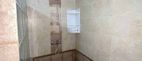 A small, tiled shower area with a showerhead and a wall-mounted water heater.
