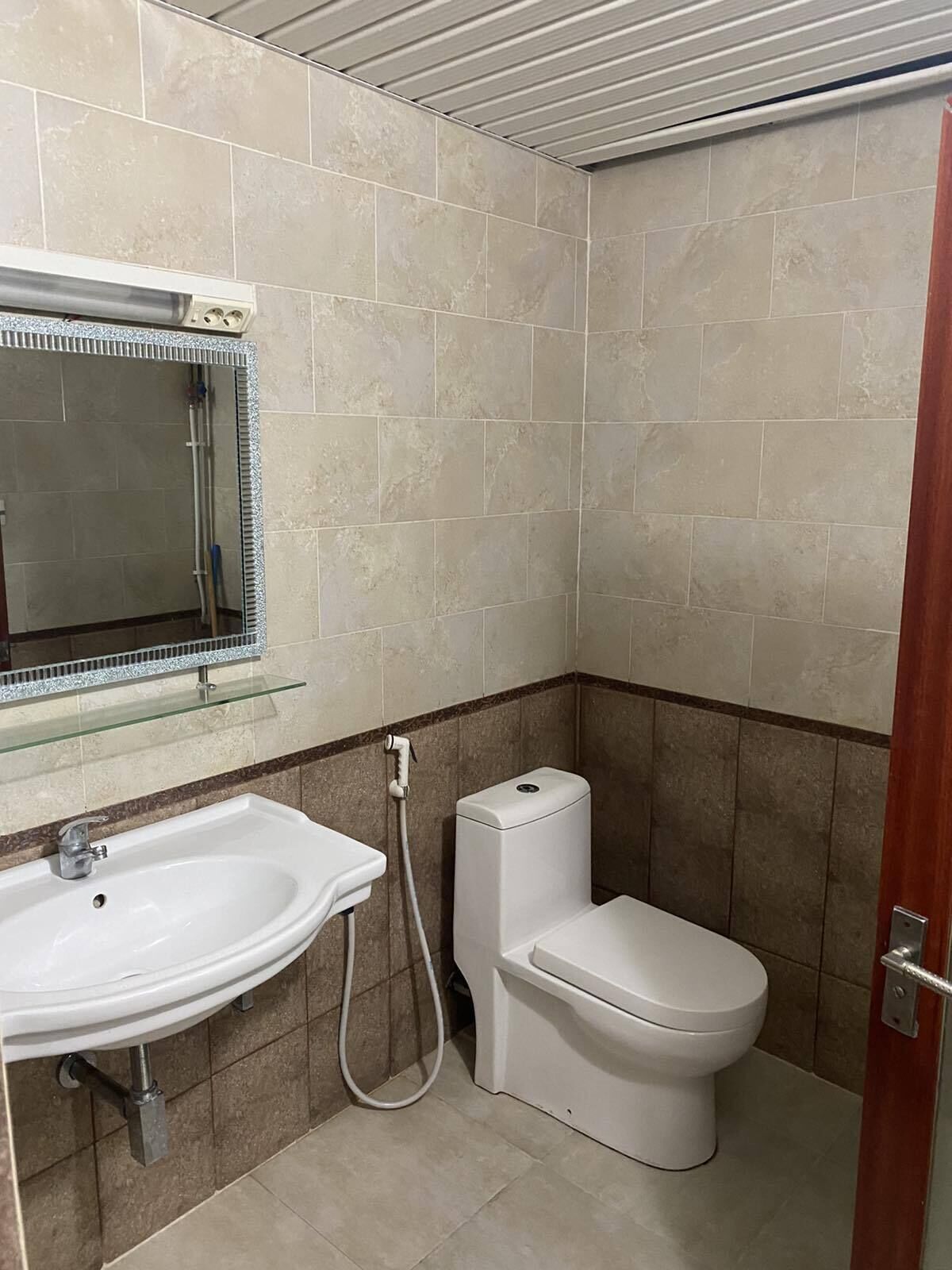 Un baño pequeño con un lavabo blanco, un inodoro y un estante de vidrio sobre el lavabo.