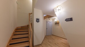 A staircase leading to a door marked with the number 4, wooden flooring, and a wall-mounted light fixture. - HOTEL SAINT AUGUSTIN (Strasbourg)