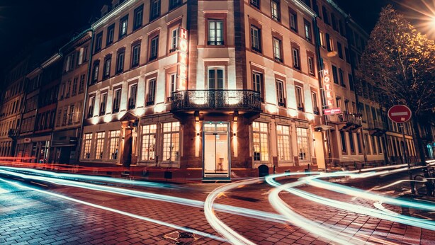 A historic hotel with a classic European architectural style, featuring a prominent balcony and illuminated signage. - HOTEL SAINT AUGUSTIN (Strasbourg)