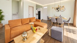 Ein modernes Wohnzimmer mit einer Couch, einem Esstisch, Stühlen und einer dekorativen Globen-Leuchte.