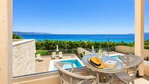 Ein Balkon mit Meerblick, einem Pool und Sitzgelegenheiten im Freien.