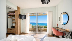 Ein Schlafzimmer mit zwei Betten, einem Schreibtisch, einem Stuhl, einem Fernseher und einem Balkon mit Meerblick.