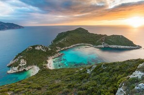 A coastal landscape with a bay, rocky terrain, and a sunset.