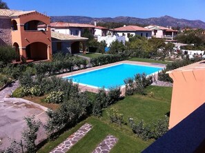 A residential area with a swimming pool surrounded by well-maintained lawns and a variety of plants. - Residence Lu Mulinu con Piscina  (San Teodoro)