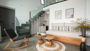 Una sala de estar moderna con un sofá, un sillón mecededor, una mesa de centro y una escalera.