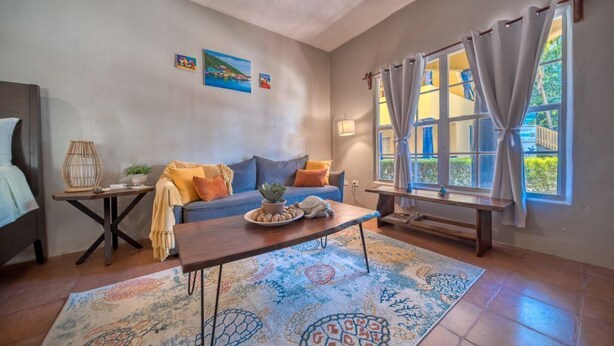 A cozy living room with a sofa, coffee table, and a large window with curtains.
