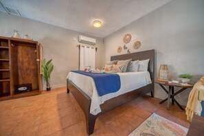 Une chambre à coucher avec un lit, une table de chevet avec une lampe, une armoire et une plante en pot.