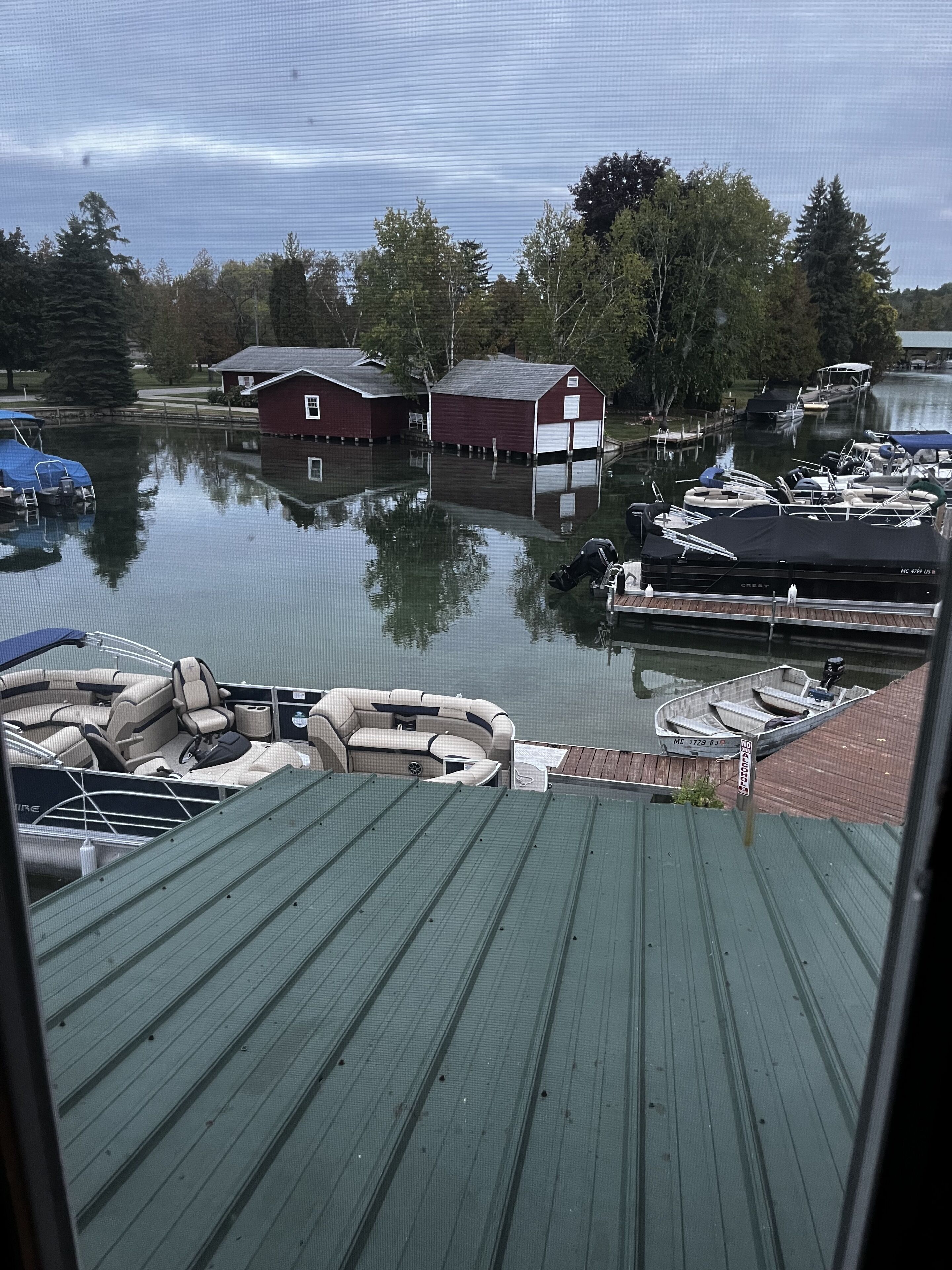 Un port de plaisance avec des bateaux amarrés, un hangar à bateaux couvert et un bâtiment rouge.