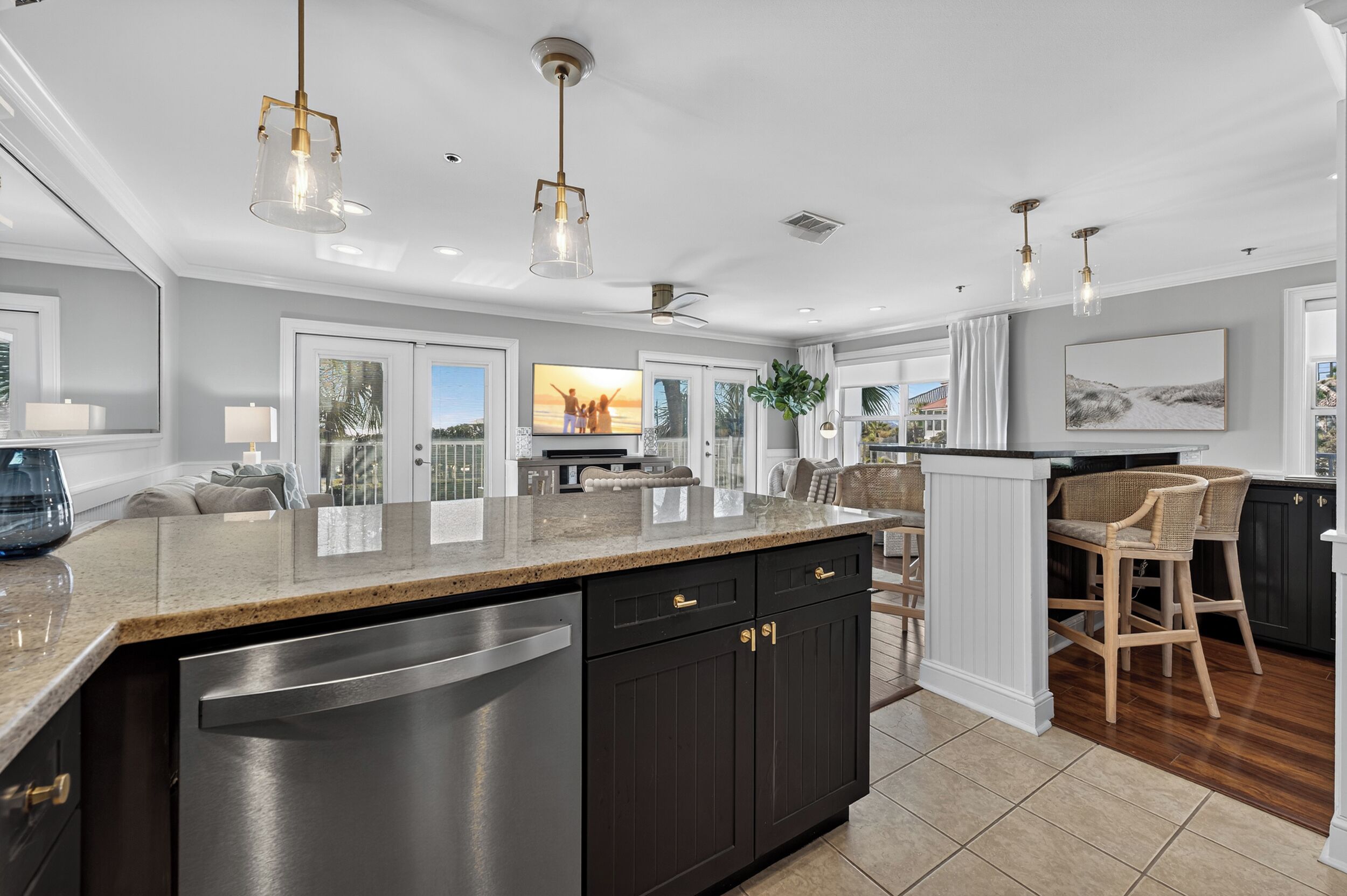 A modern kitchen with a large island, dark cabinetry, and stainless steel appliances.