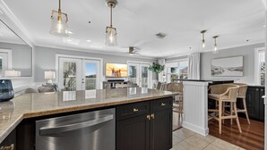 A modern kitchen with a large island, dark cabinetry, and stainless steel appliances.