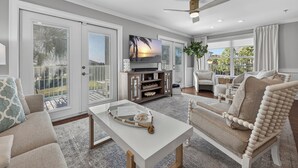 A spacious living room with a large TV, comfortable seating, and a view of the outdoors.