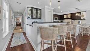 A modern kitchen with a central island, bar stools, and pendant lighting.