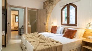 A bedroom with a large bed, a stone wall, and a window with an arched top. - Canyon 2 villa with private pool (Rethymno)