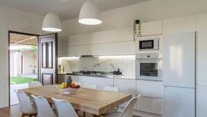 A modern kitchen with white cabinets, a wooden dining table, and white chairs. - Canyon 2 villa with private pool (Rethymno)