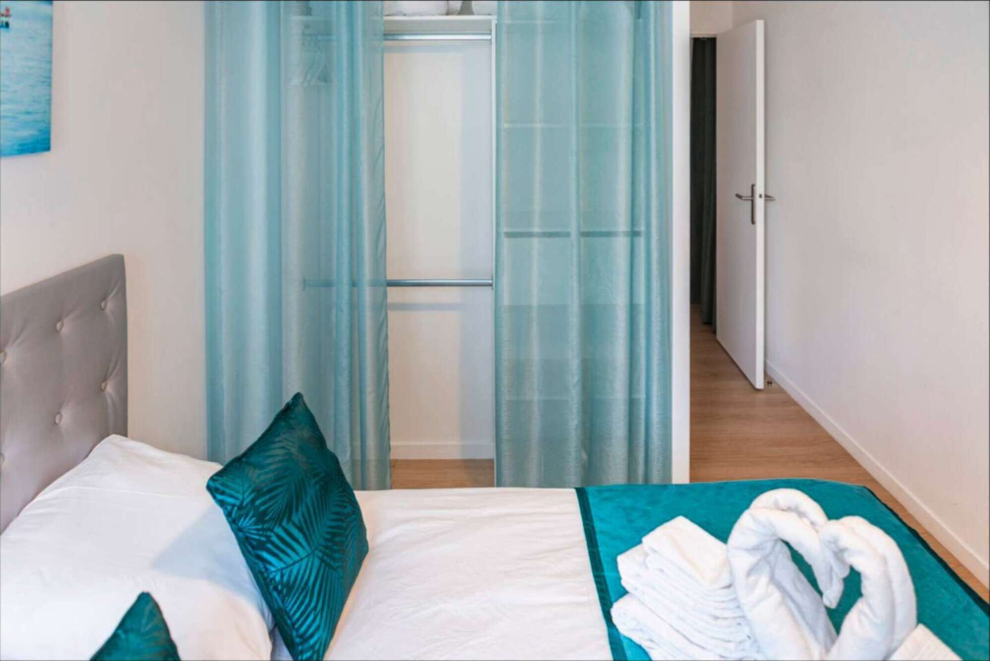 Une chambre d’hôtel avec un lit, une salle de bain dotée d’une porte en verre et un couloir menant à une autre chambre.