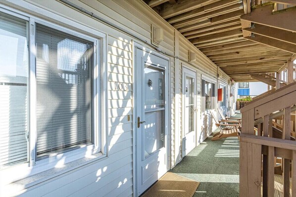A row of white cabins with sliding doors, a wooden deck, and a covered walkway. - Steps to the Beach : Sea Loft 103: (Ocean City)