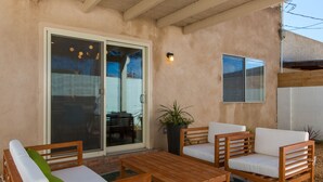 Eine Terrasse im Freien mit Holzmöbeln, einer Glasschiebetür und einem Blumentopf.