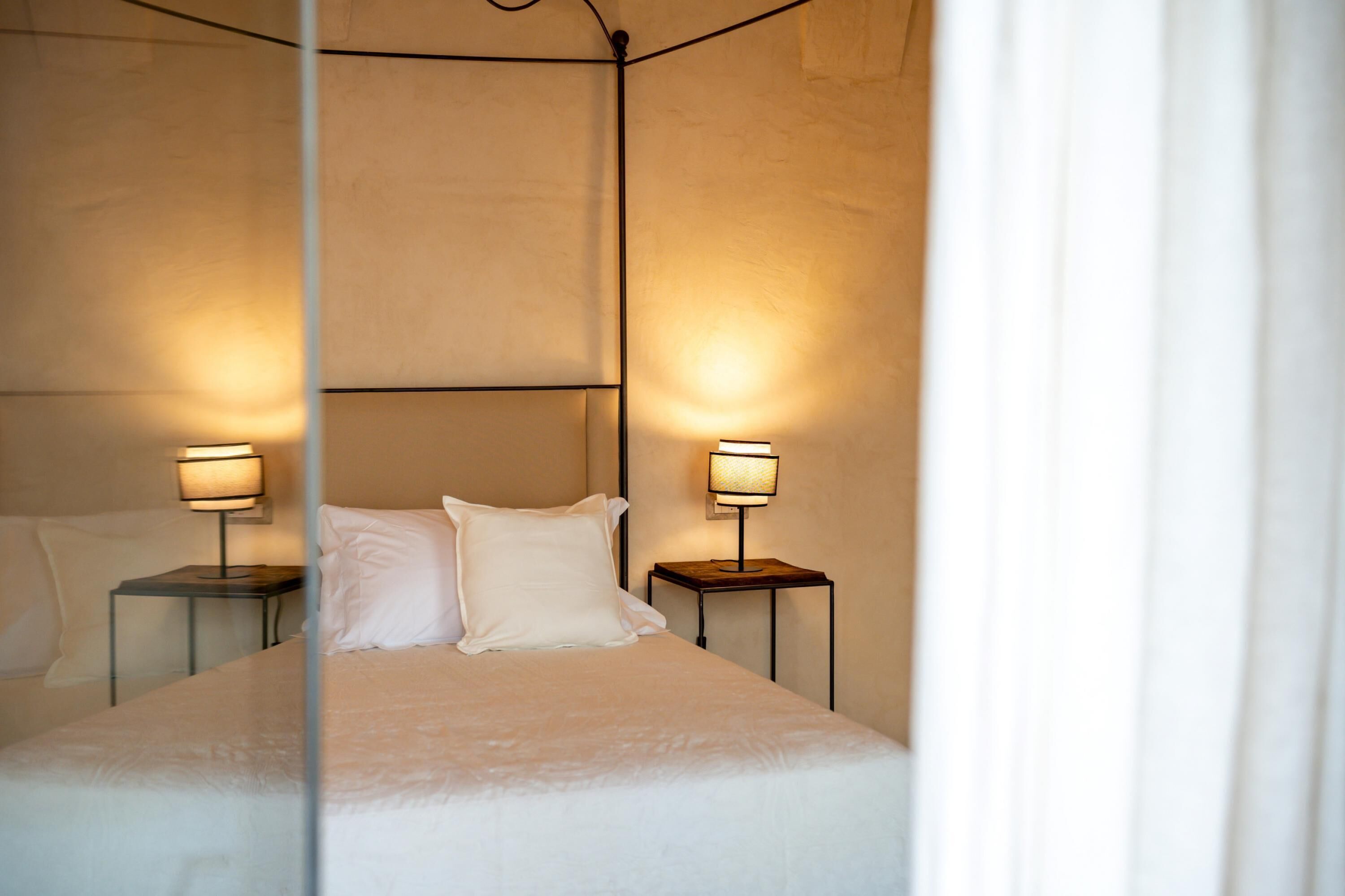 A bedroom with a bed, two bedside tables, and two lamps.