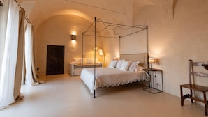 A bedroom with a four-poster bed, a sofa, and a wooden chair. - Villa Margherita in Amalfi (Amalfi)