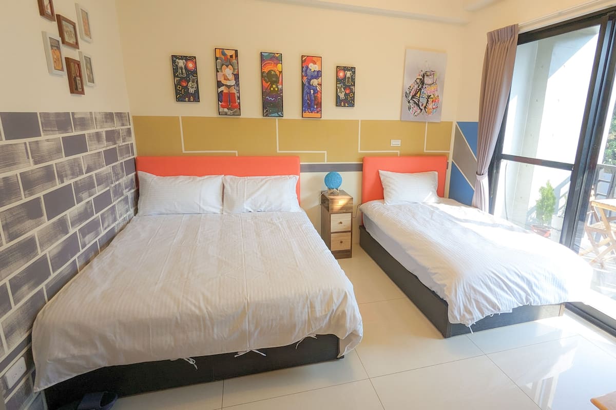A hotel room with two beds, a brick accent wall, and artwork on the wall.