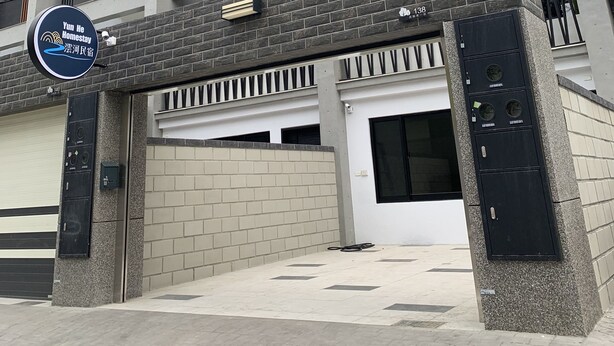 Ein mehrstöckiges Gebäude mit moderner Architektur, mit Balkonen und Metallgeländern, sowie einem Schild, das auf ein Homestay-Angebot hinweist.