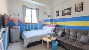 Ein kleines Zimmer mit Bett, Sofa, einem kleinen Tisch und Fernseher.