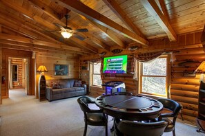 Cozy cabin interior with a central living area featuring a sofa and coffee table, a ceiling fan, and a mounted television.
