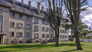 A building with multiple windows and a grassy courtyard.