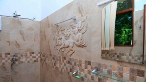 Un baño con un espejo grande, una repisa de vidrio y un muro decorativo con un relieve de caballo.