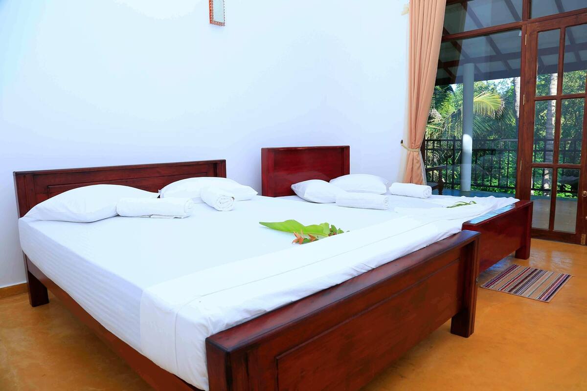 A double bed with white linens, a wooden headboard, and a small bedside table with a lamp.
